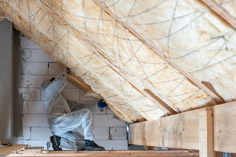 Ouvrier installant de l'isolation en laine de roche dans les combles