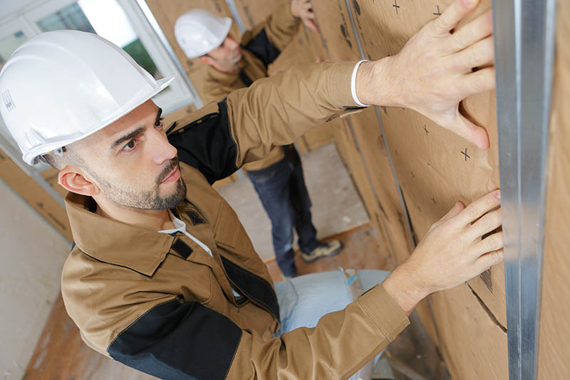Technicien installant un isolant phonique minéral